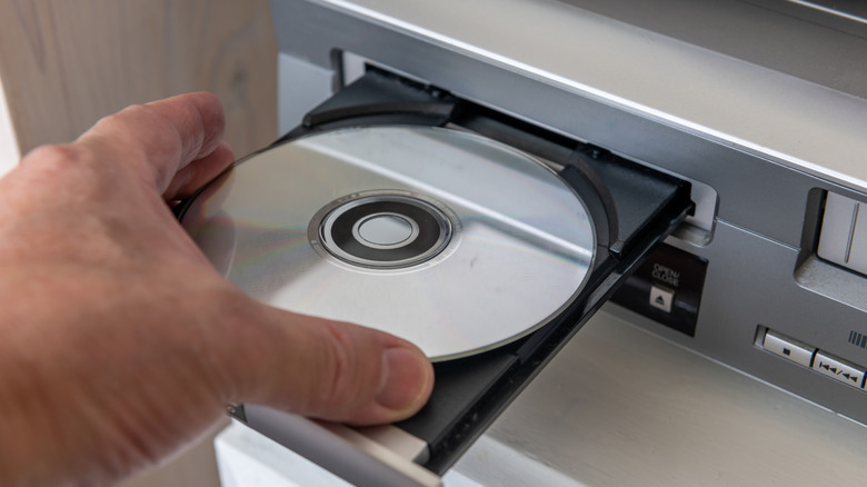 A person placing a DVD in a DVD player.