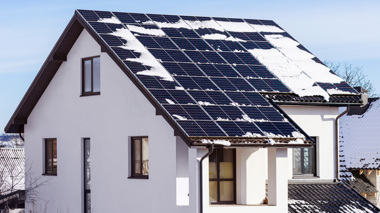 solar panels on the roof of a home covered in snow