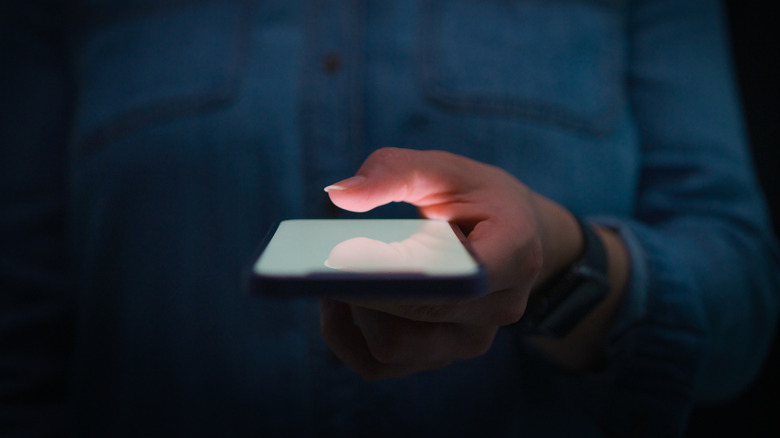 Person holding a phone on a dark background