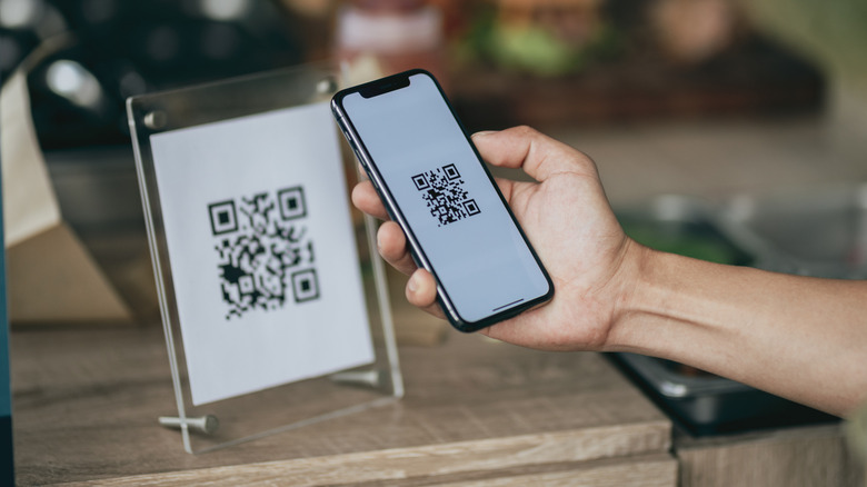 Someone scanning a QR code on a sign in an establishment.
