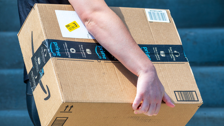 A person shown carrying an Amazon package.