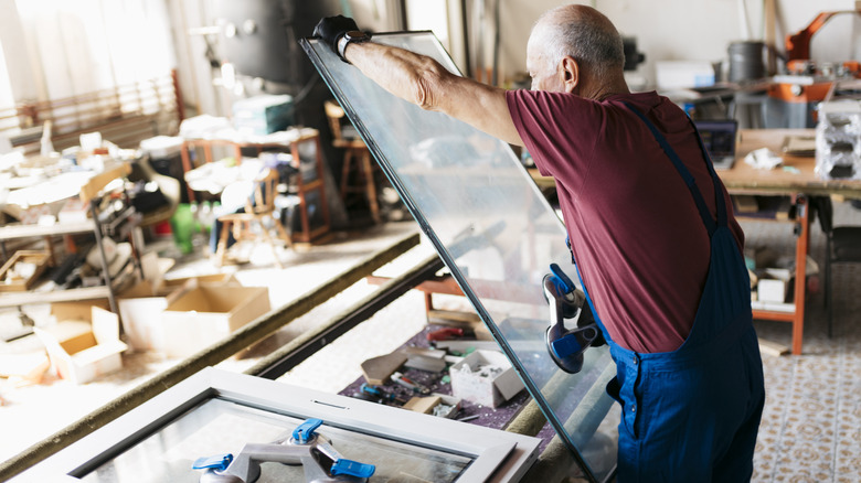a man placing glass in a window frame in a shop