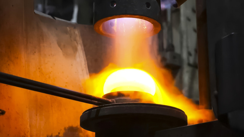 Molten glass gets blown in a factory.