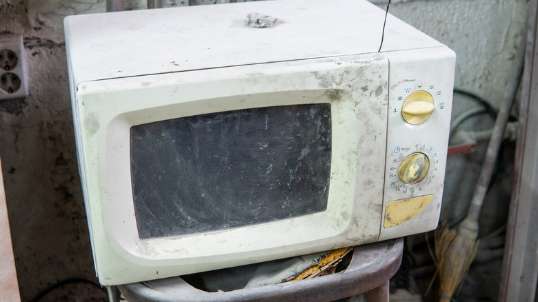 An old microwave oven with lots of marks and scuffs on the front.
