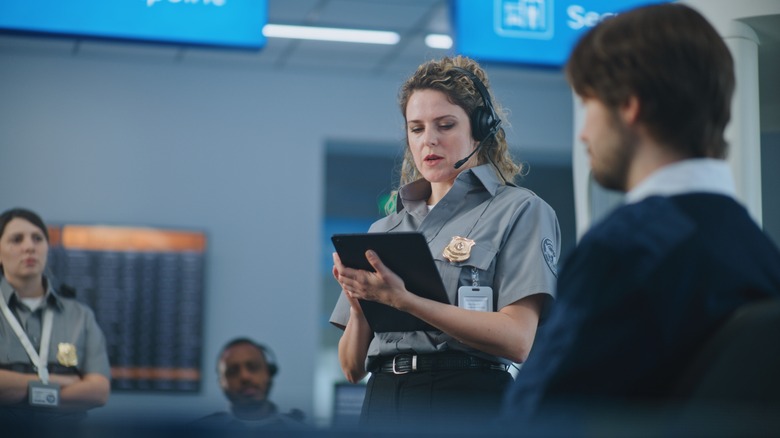 TSA agent with tablet administering manual screening.
