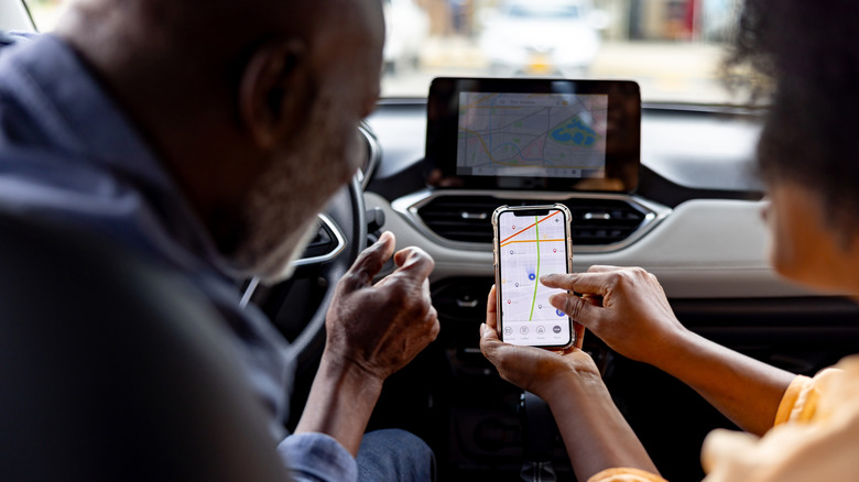 Two people looking at a navigation app inside a car
