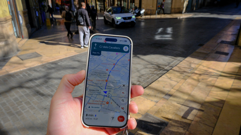 A hand holding a smartphone with Google Maps on it to walk around a city