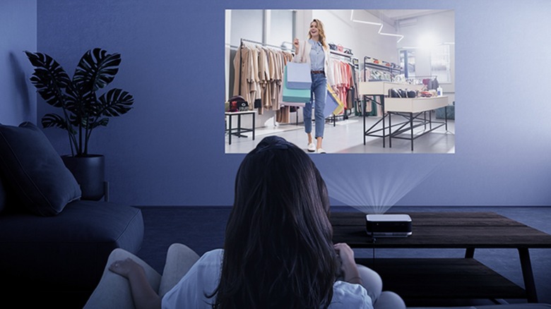 A woman watching a TV show with the Epson Lifestudio Pop Plus projector on a wall