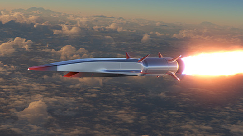 A metallic hypersonic missile with red accents flying above clouds
