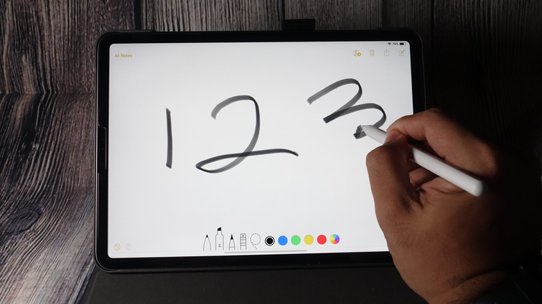 Close up of a hand writing "1 2 3" on an iPad with an Apple Pencil