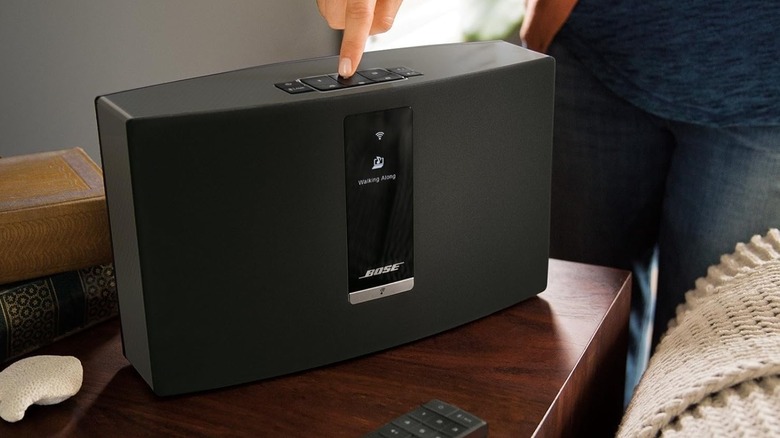 A person pressing the buttons on a Bose SoundTouch 20 Series III wireless speaker.