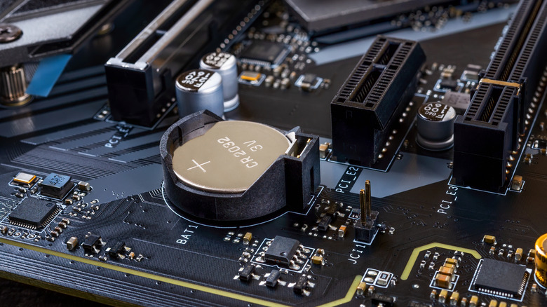 Close up of a CMOS battery in its dedicated slot on a motherboard.