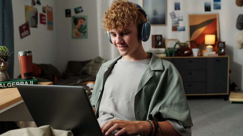 a young man using a gaming laptop in his room