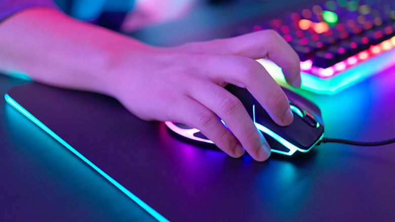 Hand resting on gaming mouse in claw position.