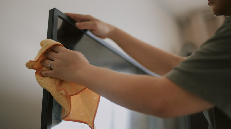 Close-up of a person wiping their monitor screen with a microfiber cloth