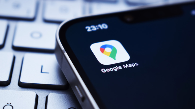 The Google Maps app icon on an iPhone with a laptop keyboard in the background