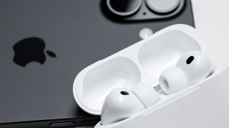 AirPods Pro 3 inside their case, on top of an iPhone 17 model.