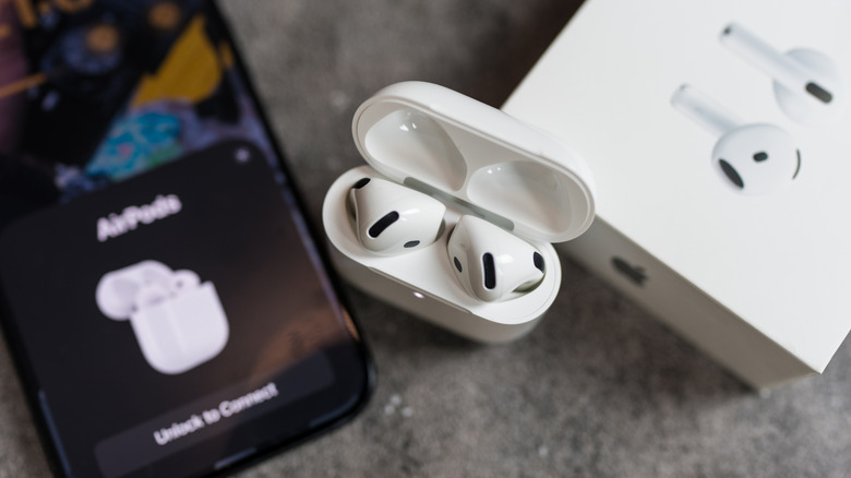 The AirPods 4 between an iPhone and their retail box.
