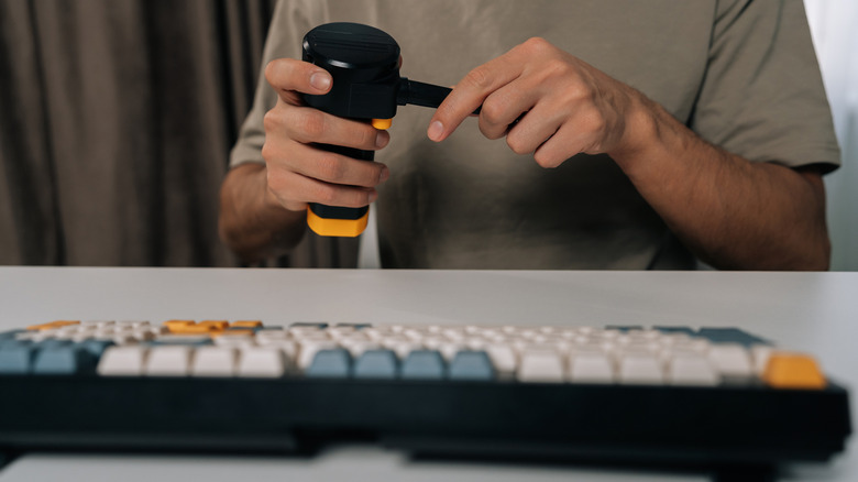 A man setting up an electronic duster in front of a keyboard.