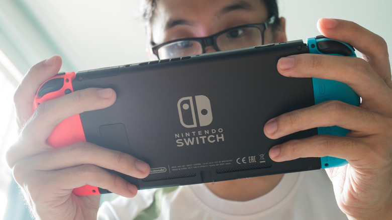 Close up of someone playing their Nintendo Switch console looking down.