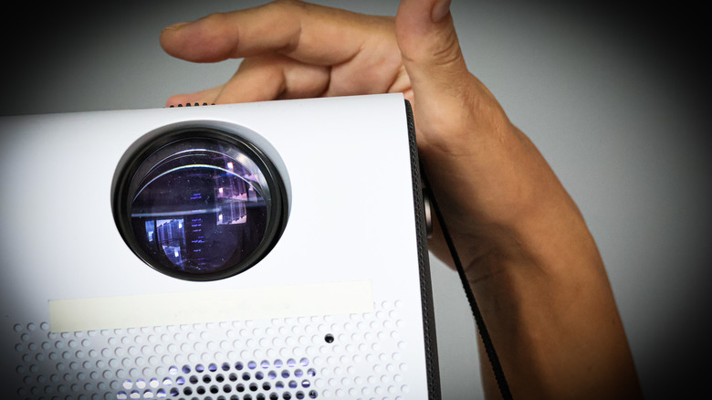 Person turning on a digital projector.
