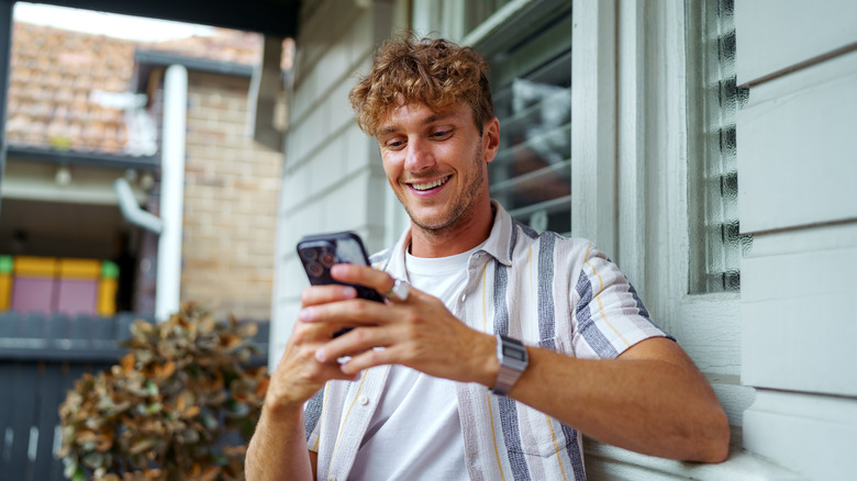 A man smilling while using an iPhone
