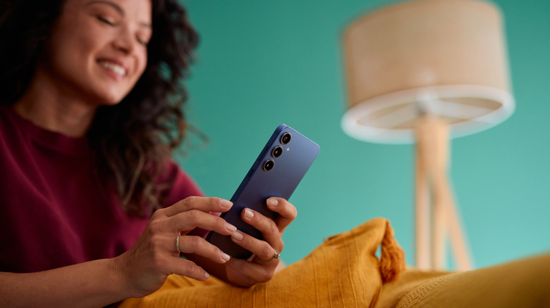 A woman smilling while using an Android phone