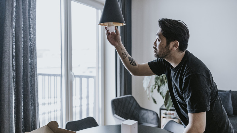 A person installing a smart light bulb in their home