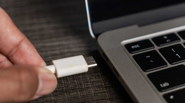 A person plugging a USB-C cable into a laptop.