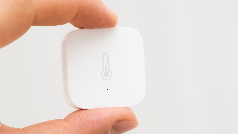 A small white smart sensor with a thermometer icon.