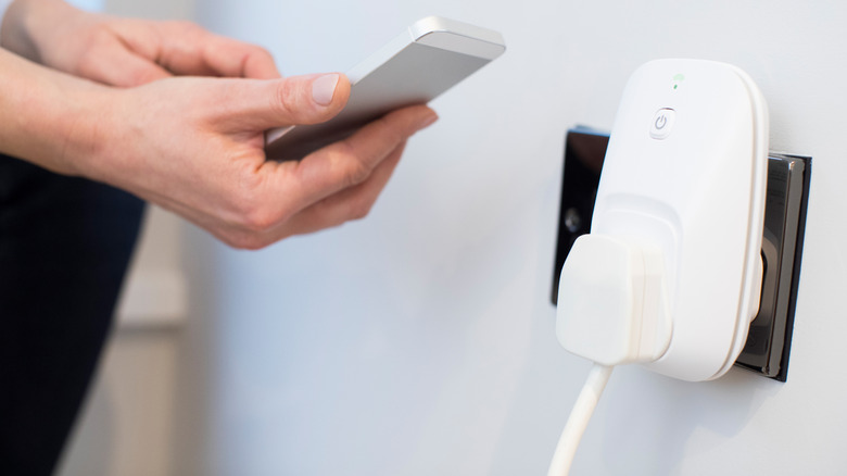 A woman controlling a smart plug with her smartphone