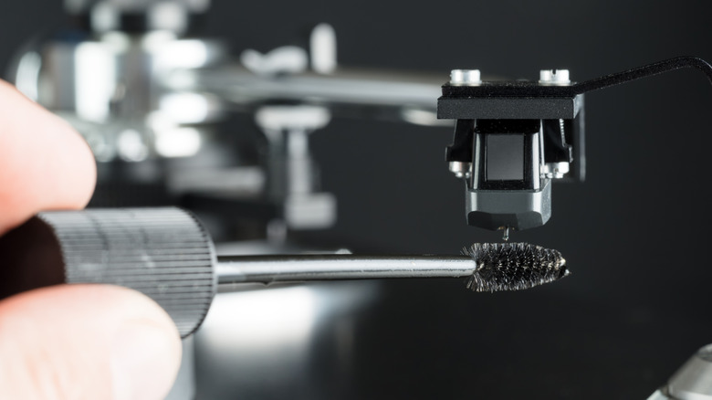 Photo of a person cleaning a turntable stylus with an antistatic brush.