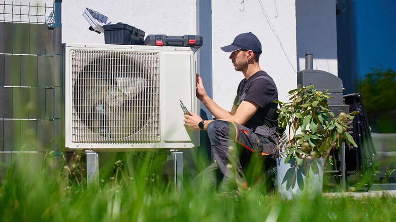 A technician services an outdoor HVAC unit with tools visible.