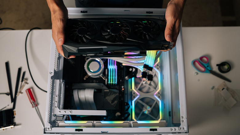 Someone holding the graphics card with their hands above their PC.