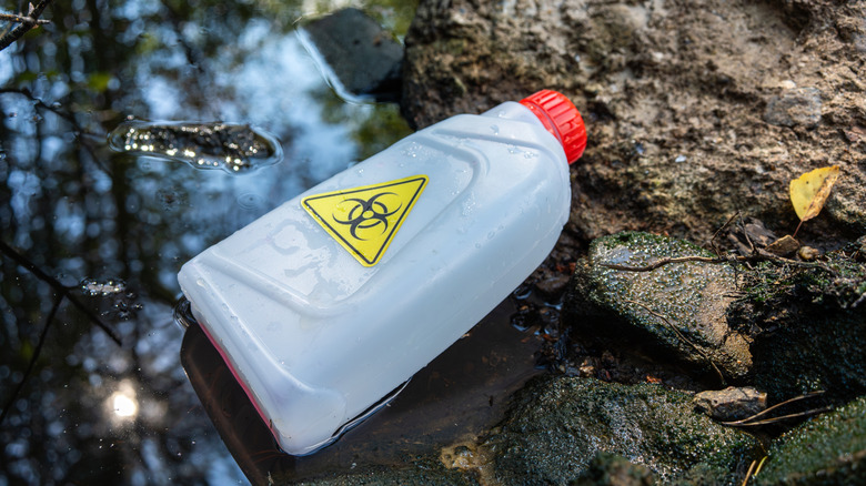bottle in stream with warning symbol on it, concept of environmental contamination