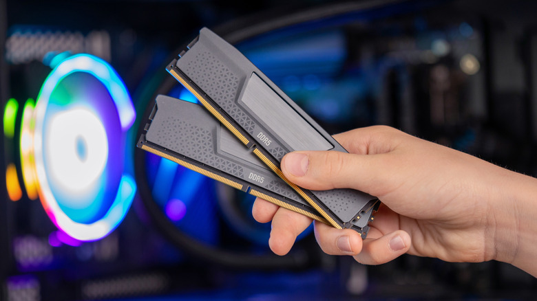 Person holding DDR5 RAM modules in front of open computer case