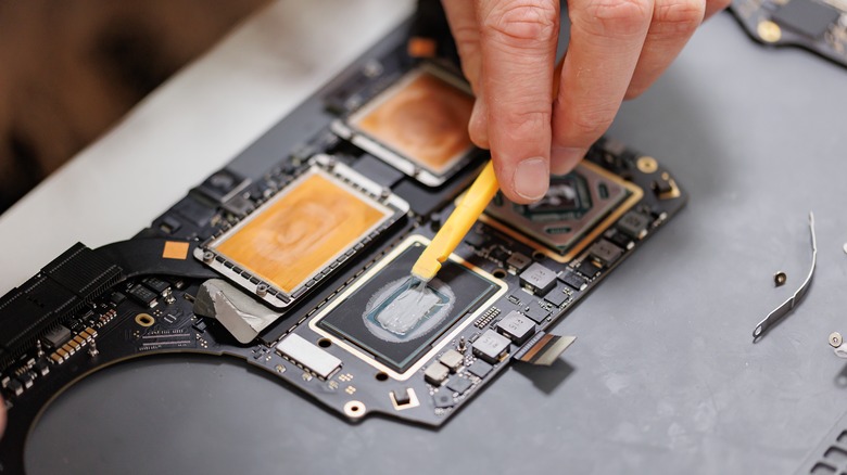 A person applying thermal paste to a PC board.