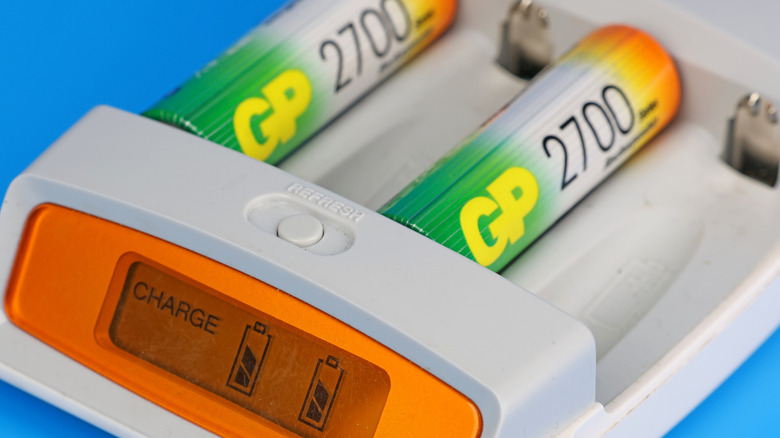 Rechargeable batteries connected to a charging adapter with the screen visible.