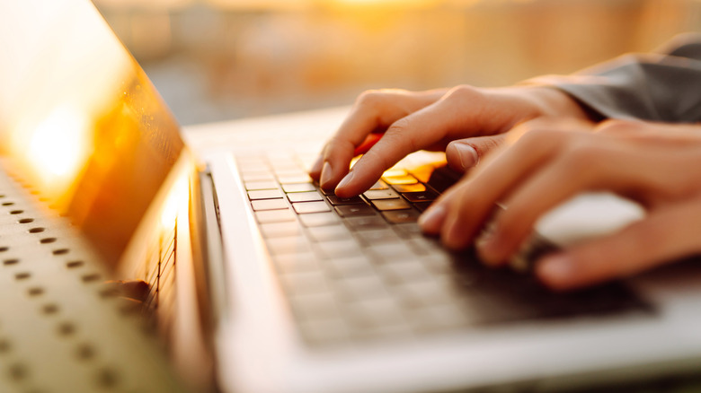 Hands typing on a laptop