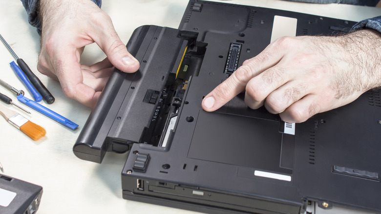 A technician removing a battery from a laptop.