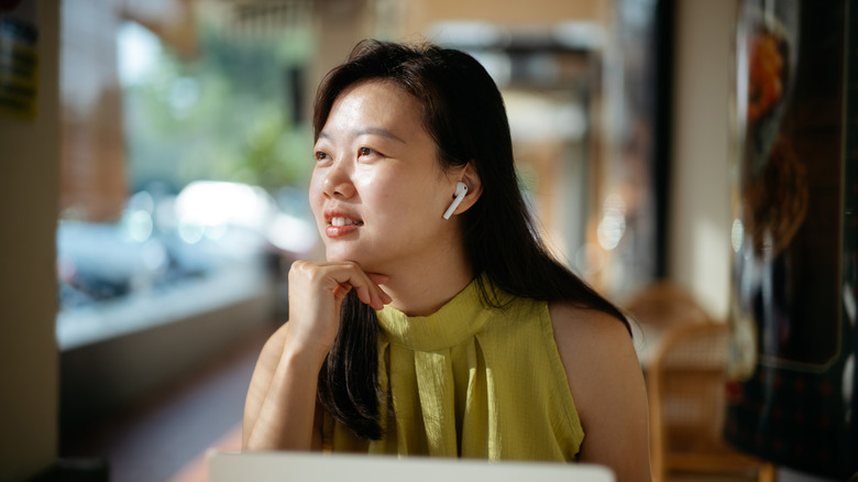 A woman looking into the distance with AirPods in her ears