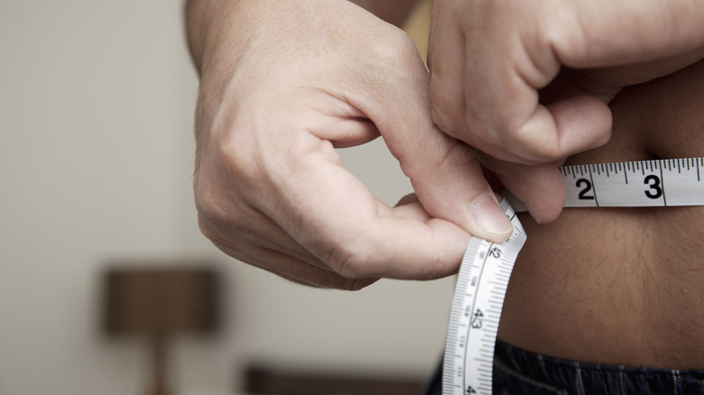 man measuring his waistline