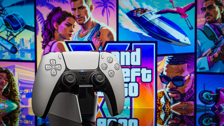 A PS5 controller on a charging dock with a "GTA 6" poster in the background