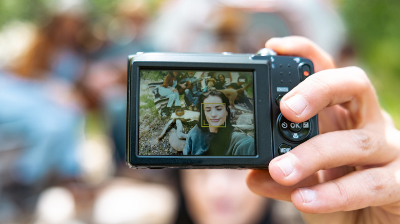 Person taking a group selfie using an old digital camera