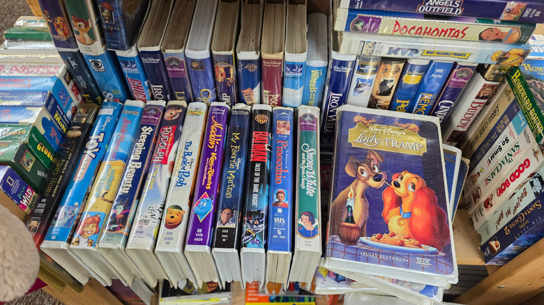 Various VHS tapes stored on a shelf inside their cases and sleeves.