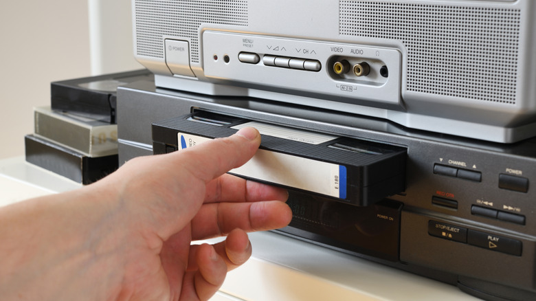 Someone inserting a VHS tape into a player.