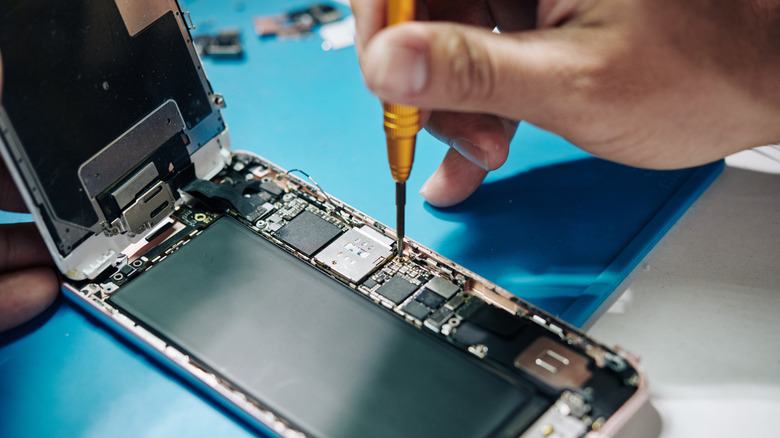 A technician replaces the SIM tray of a smartphone.