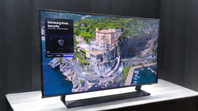 a Samsung TV showing picture display and Samsung Knox Security while standing on a wooden surface
