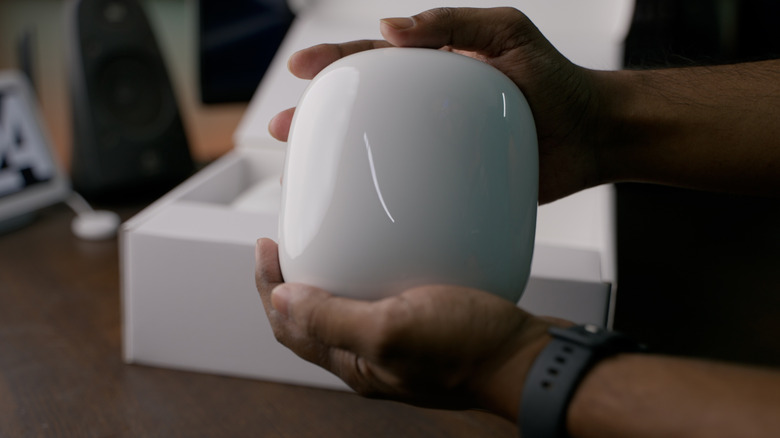 Close-up of a person holding a white Google Nest Wi-Fi Pro router