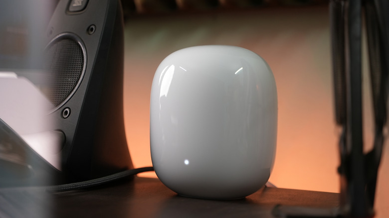 A white Google Nest WiFi Pro router on top a wooden desk